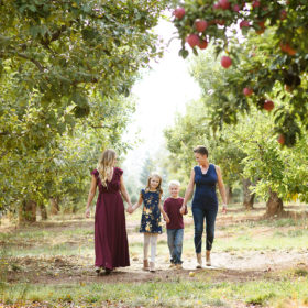 Moms walking with daughter and son in between apple orchards in Apple Hill