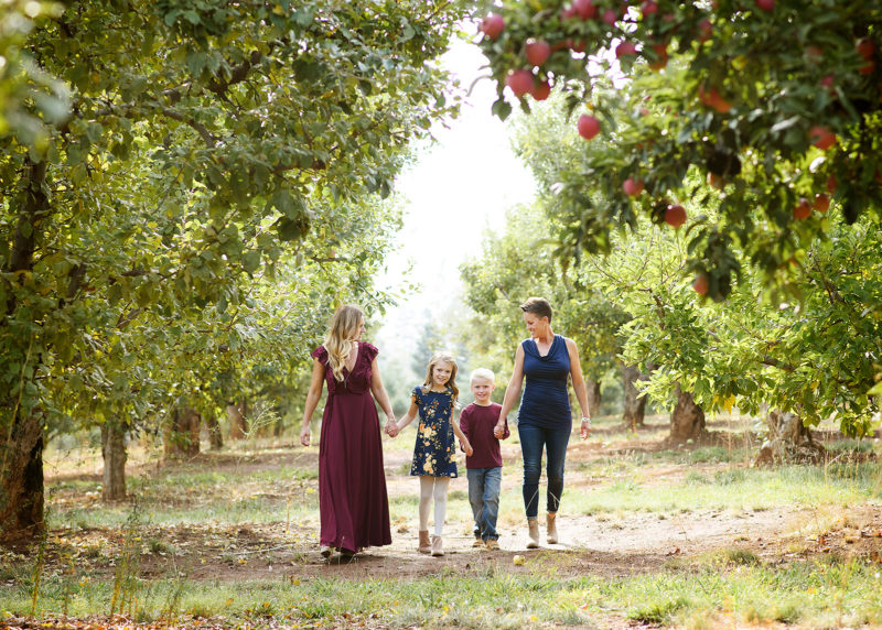Moms walking with daughter and son in between apple orchards in Apple Hill