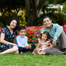 Family sits on the grass in front of colorful flowers at the Sacramento Capitol