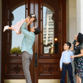 Dad lifting up daughter while mom and brother watch in front of Sacramento Capitol doors