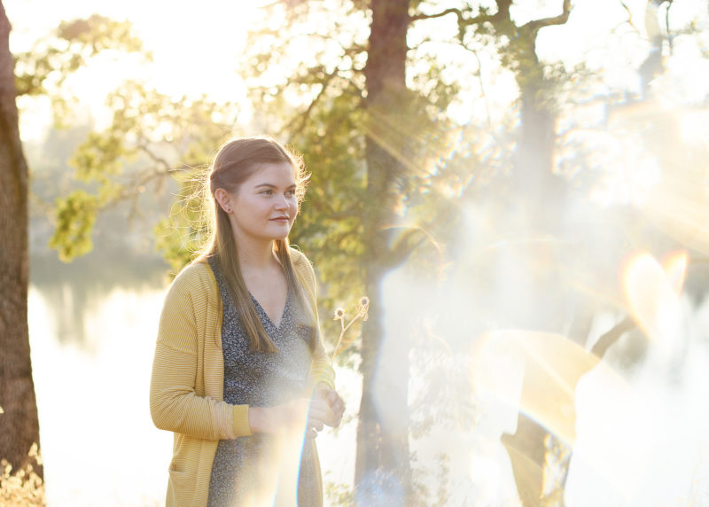 High school senior girl standing next to tree in sunlight with lens flare Folsom