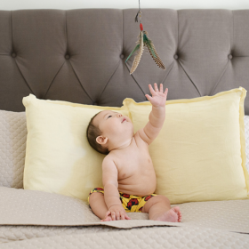 6 month baby boy reaching for fishing fly on bed Sacramento
