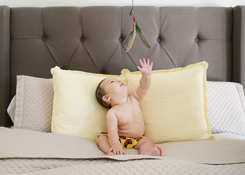 6 month baby boy reaching for fishing fly on bed Sacramento