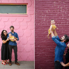 Mom and dad hold baby daughter in front of colorful pink and purple brick walls in midtown Sacramento