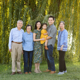 Grandparents and mom and dad holding toddler with willow tree in background