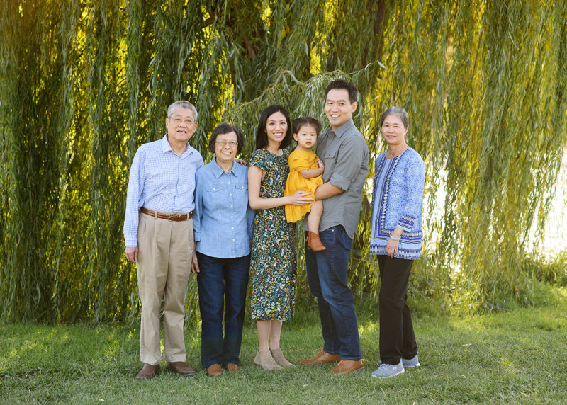Grandparents and mom and dad holding toddler with willow tree in background