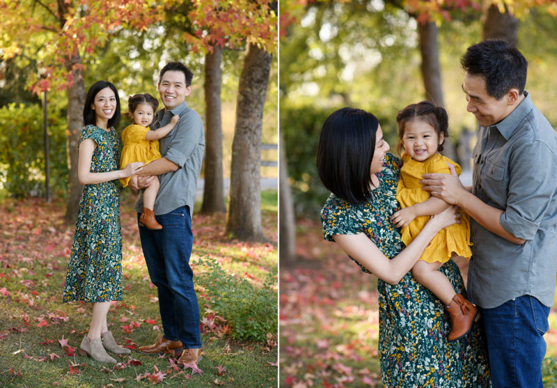 Mom and dad hold toddler daughter while standing on autumn leaves foliage in Bywater Hollow Lavender Farm