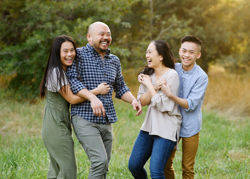 Asian family laughing and hugging each other during golden hour in Sacramento