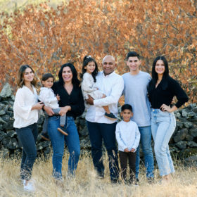 Large family posing in front of autumn foliage and dry grass