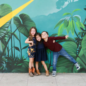 Sisters and brother hugging in front of midtown mural in Sacramento
