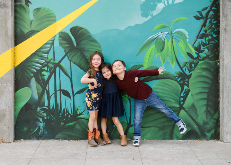 Sisters and brother hugging in front of midtown mural in Sacramento