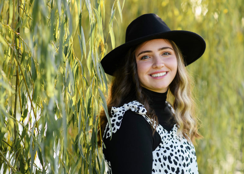 Teenage girl smiling with hat with willow tree in background in Bywater Hollow Lavender Farm