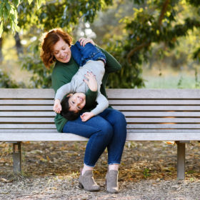Aunt holds nephew upside down on the bench at Davis Arboretum