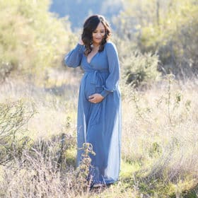 Pregnant woman in blue dress standing in dry grass Auburn