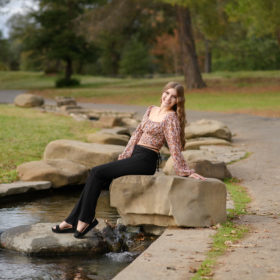 High school senior girl sitting on a rock by a pond in Sacramento