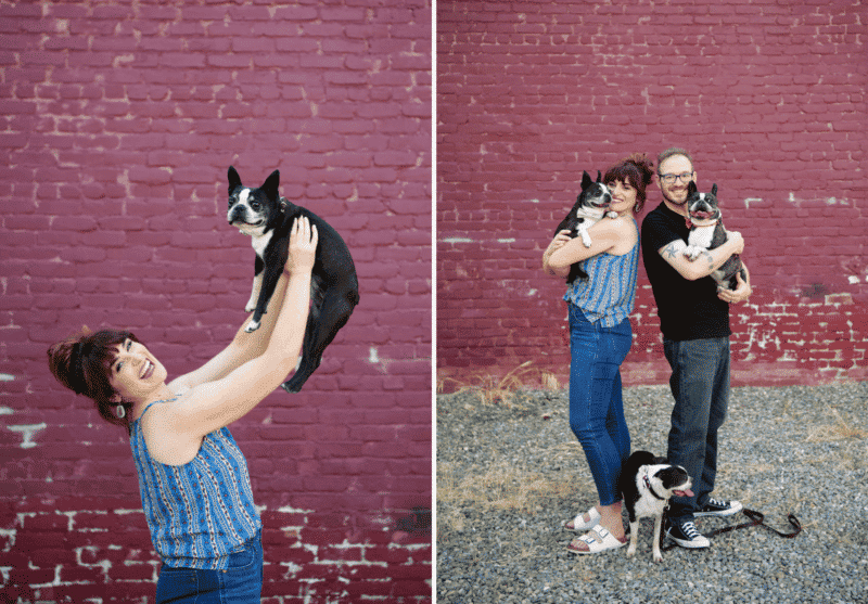 couple posing with boston terrier dogs in front of red brick wall in downtown sacramento california