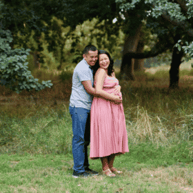 maternity photo shoot in northern California mom and dad in a field pink dress