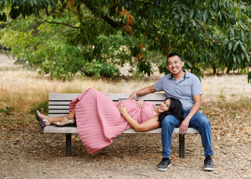 maternity photo shoot with couple in northern california laying on a bench