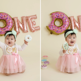 one year old birthday studio photos cake smash with donuts pink sprinkles baby girl smiling and laughing