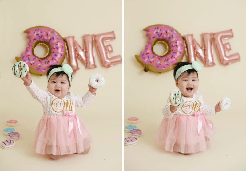 one year old birthday studio photos cake smash with donuts pink sprinkles baby girl smiling and laughing