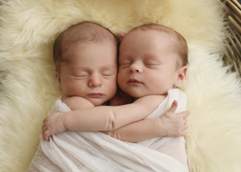 twin newborn baby girls hugging in a studio photo shoot