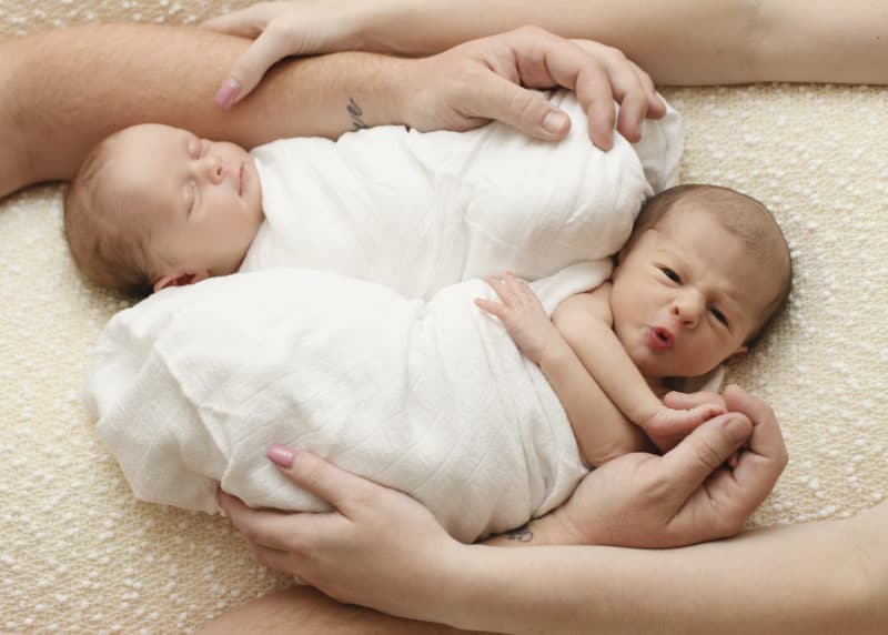 newborn baby twin girls in a studio photo shoot with mom and dads arms