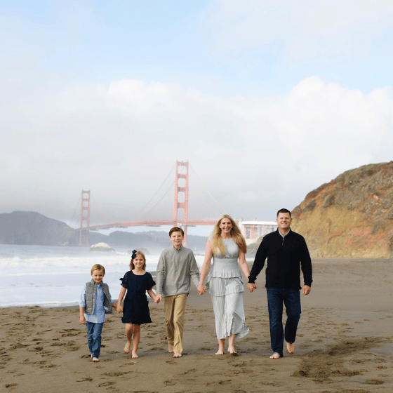 family holding hands on the beach in front of the golden gate bridge in san francisco california