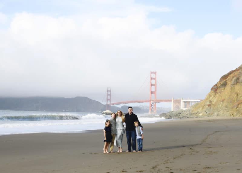 family smiling on the beach in front of the golden gate bridge in san francisco california