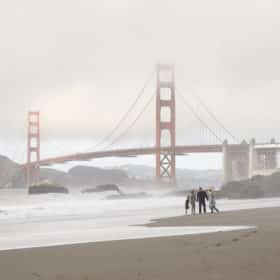family holding hands on the beach in front of the golden gate bridge san francisco