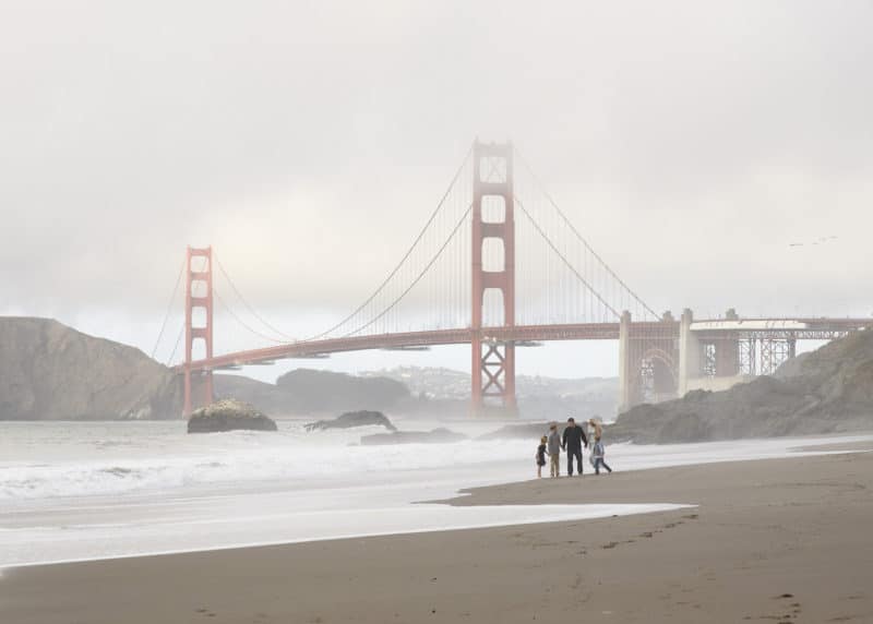 family holding hands on the beach in front of the golden gate bridge san francisco