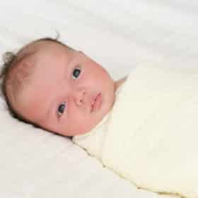 newborn baby boy swaddled in white blanket