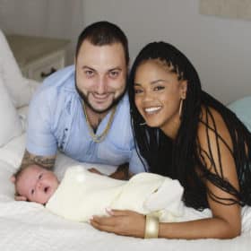 mom and dad laying with newborn baby boy at-home photo session
