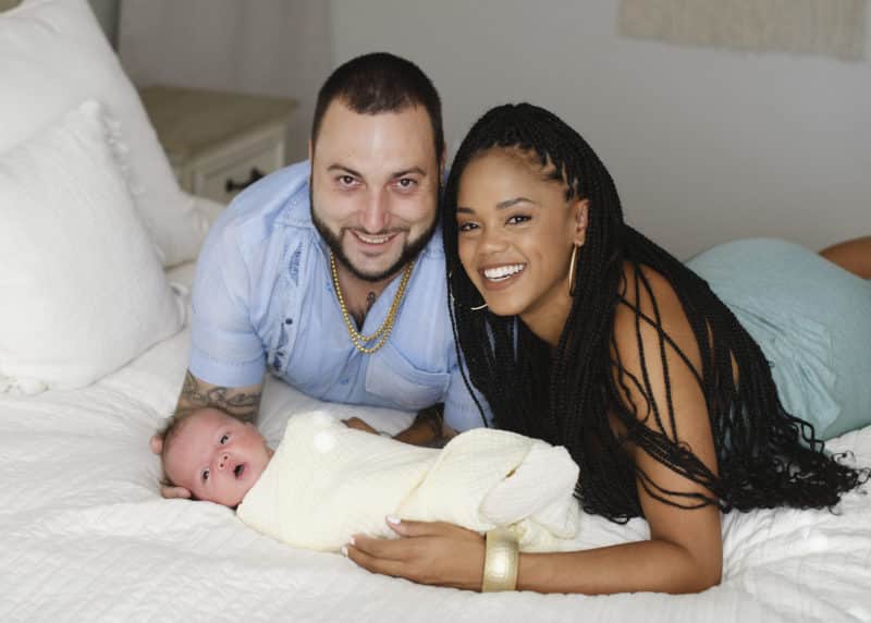 mom and dad laying with newborn baby boy at-home photo session