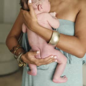 mom holding newborn baby boy bottom at-home newborn session