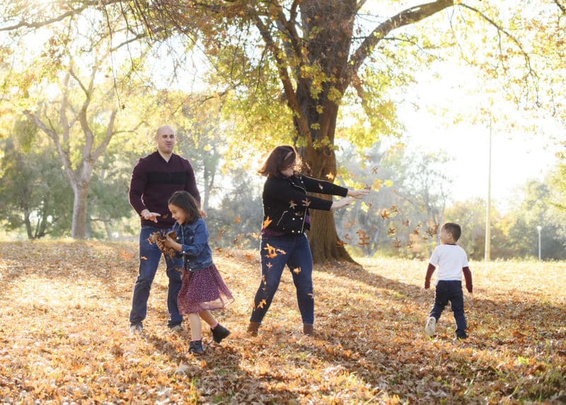 family of four throwing leaves in the fall during photo session