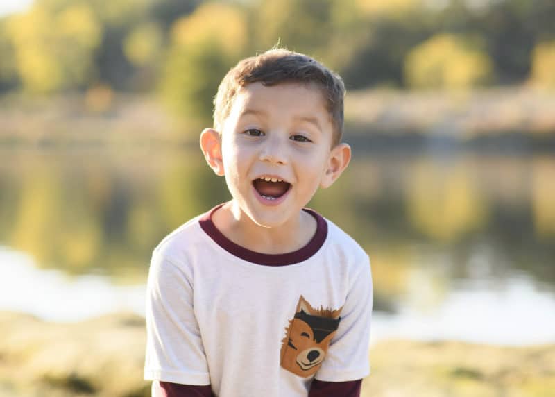 young boy smiling near the river during fall family photos rancho cordova california