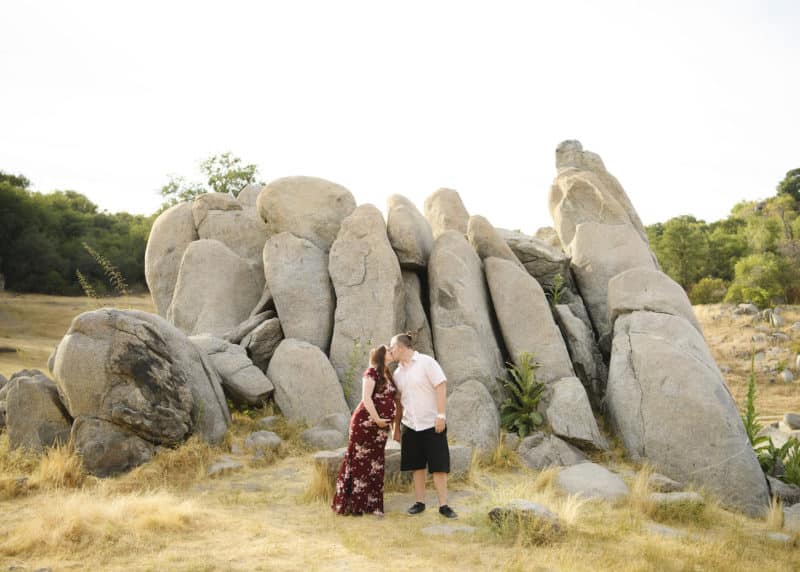 mom and dad kissing in front of rock formation maternity photo shoot granite bay california