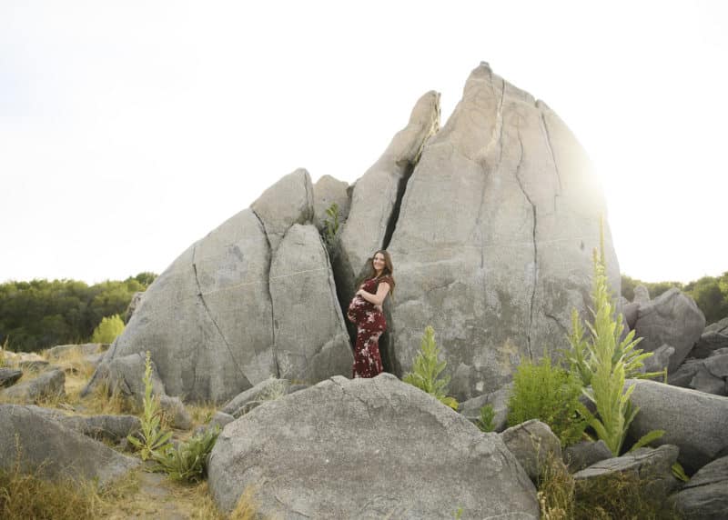 woman holding her pregnant belly during maternity shoot among the rocks granite bay california