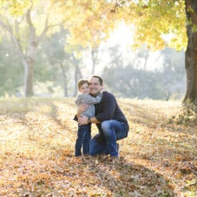 dad and son hugging smiling in the fall leaves