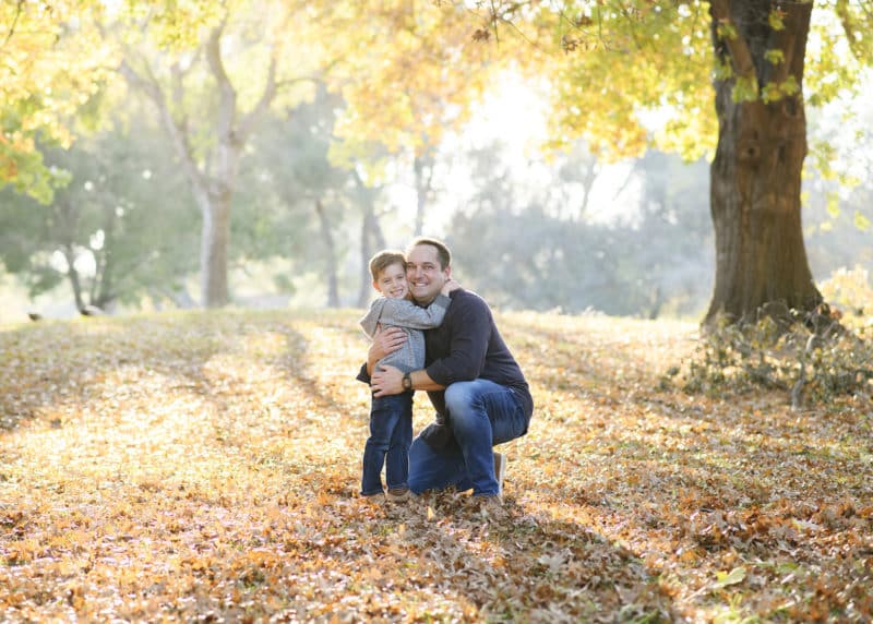 dad and son hugging smiling in the fall leaves