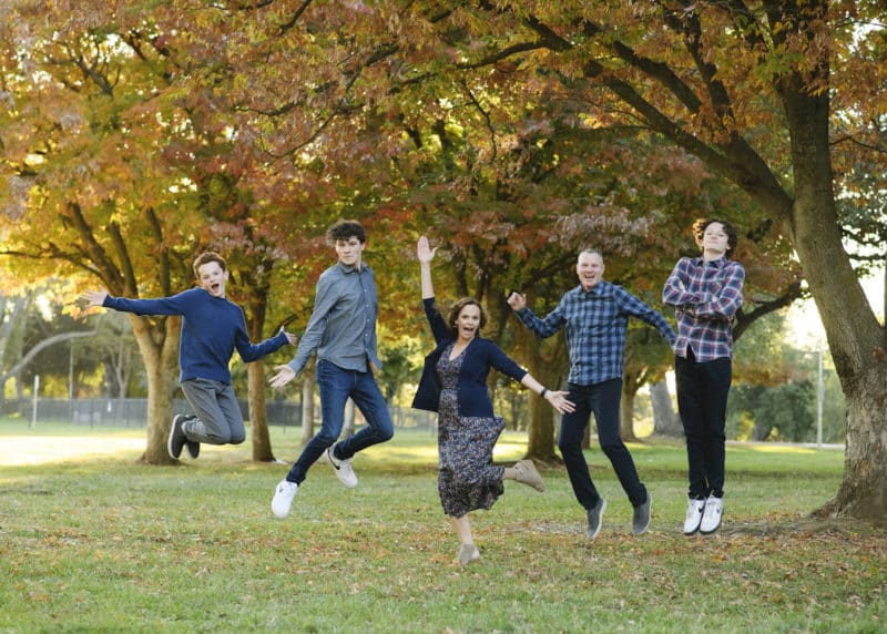family of five jumping photo among fall trees