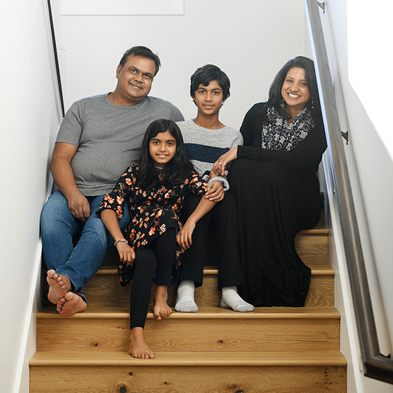 family of four smiling on staircase at home photo session