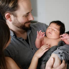 dad with newborn son smiling at home photo session