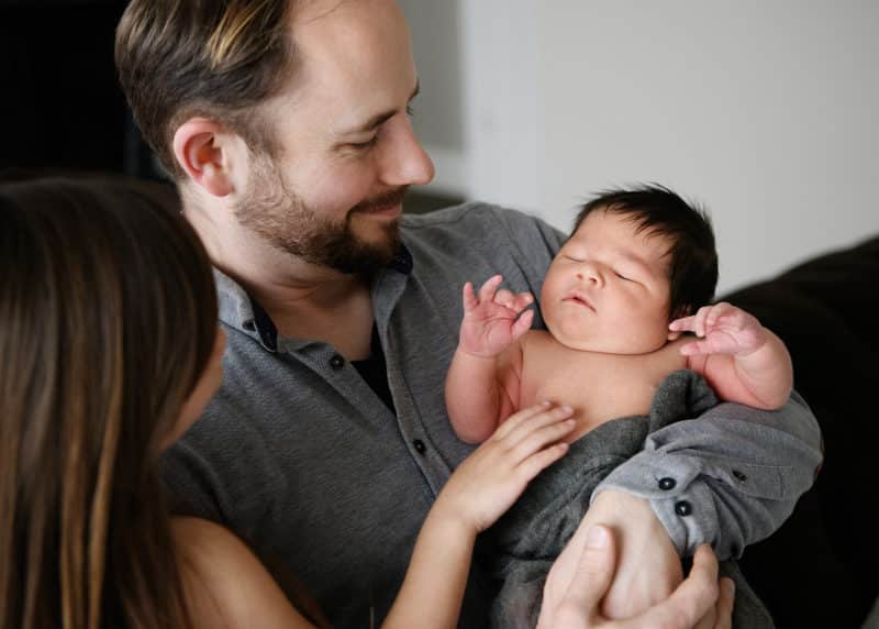 dad with newborn son smiling at home photo session