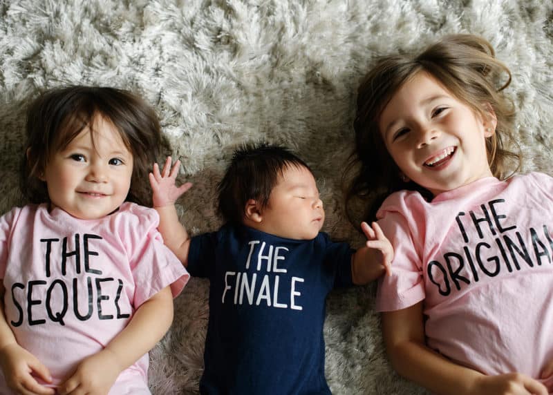 sisters posing with newborn baby boy at home photo session