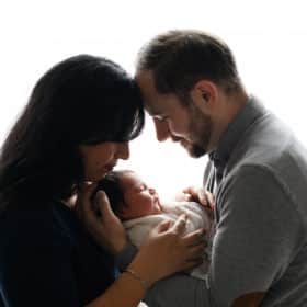 mom and dad holding newborn baby boy at home