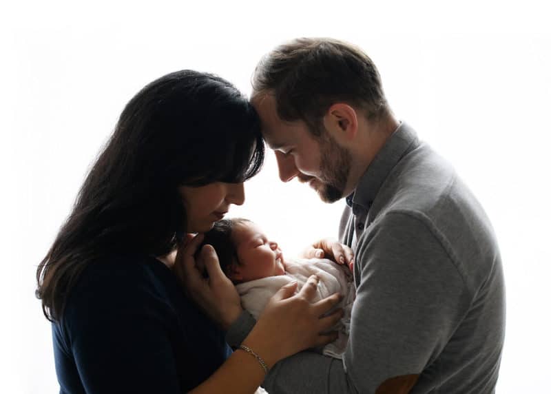 mom and dad holding newborn baby boy at home