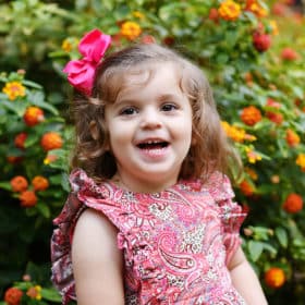 young girl smiling in front of flowers in natural light