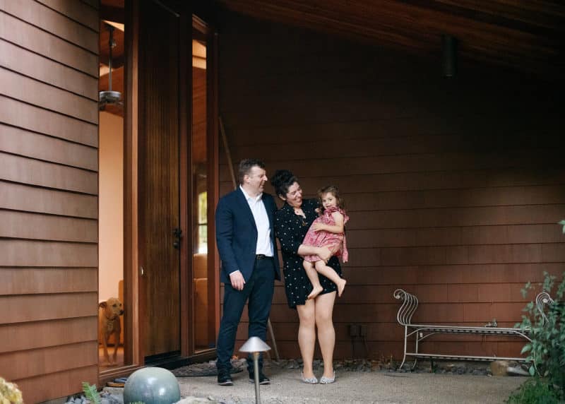 family of three posing by front door