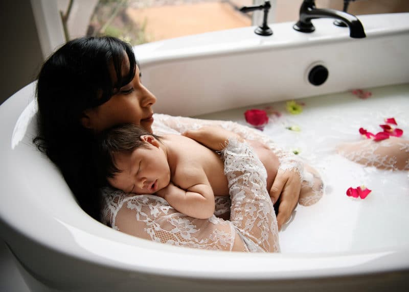 mom with newborn baby boy in milk bath at home